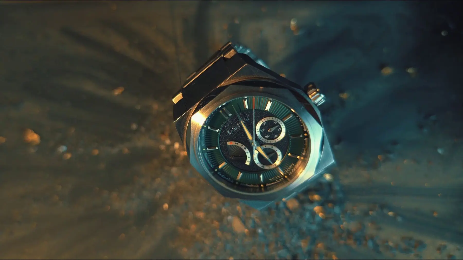 Cinematic product-film frame showing a luxury watch surrounded by gold particles